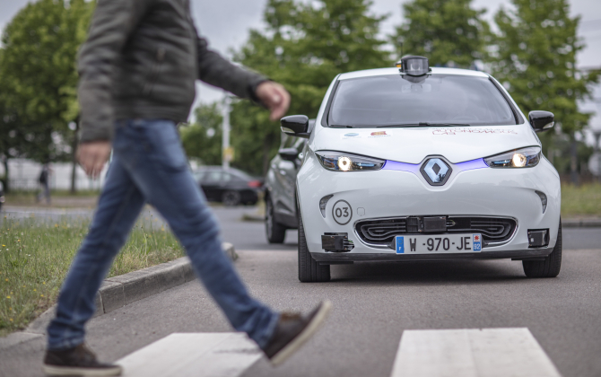 Un piéton traverse la rue devant une Renault Zoe électrique et autonome, mise en circulation dans le cadre du projet "Rouen Normandy Autonomous Lab".