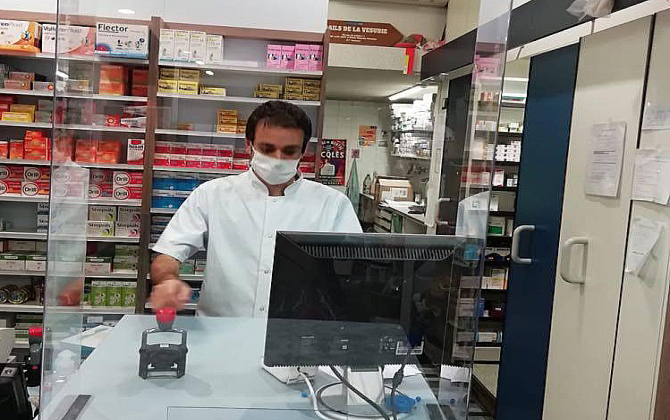 Pharmacien derrière un plexiglas de protection
